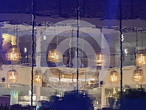 A blurry reflection of a restaurant with lights hanging from the ceiling