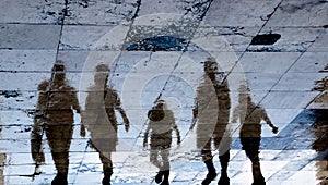 Blurry reflection shadow silhouette on wet city sidewalk of mysterious people walking away the night