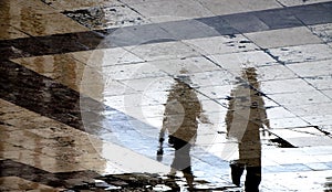 Blurry reflection shadow silhouette on a wet street of  people walking on a rainy day