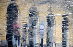 Blurry reflection silhouettes of people walking on a rainy day