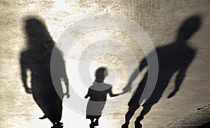 Blurry shadow silhouette of a family walking on a promenade on a summer day