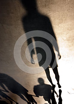 Blurry silhouette shadow of one young woman and family with children walking behind her