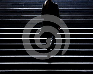 Blurry silhouette of young elegant woman climbing up the city st