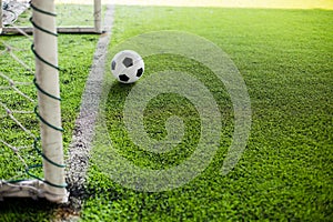 Blurry soccer ball on green artificial turf move to goal at front of the goal line