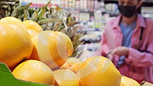 Blurry video of a woman in a protective mask making purchase putting bananas in the grocery basket and goes to the shelf