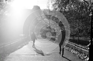 Blurry view of silhouette of people at public park in London with bright sunlight through building for background or backdrop