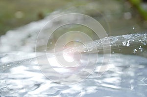 Blurry water flow and splashing with sunlight in garden