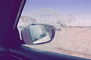 Blurry wet abstract glass background. Rear back view car mirror with rain drops during rainy bad weather. Sadness loneliness