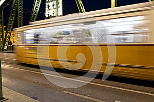 The blurry yellow train move on the speed on the bridge in Hungary