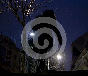 Blurry person walking alone in snowy city night