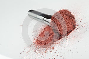 A blush brush, with pink loose blush