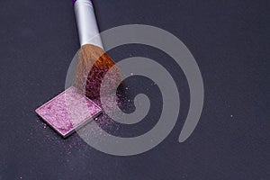 Blush or face powder pink eyeshadow and brush on black background.