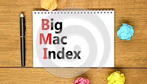 BMI big mac index symbol. Concept words BMI big mac index on white note on a beautiful wooden table wooden background. Pen.