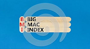 BMI big mac index symbol. Concept words BMI big mac index on wooden stick on a beautiful blue table blue background. Business and