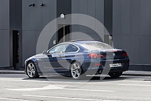 BMW 640i F13 parked on the city street. Dark blue BMW 6 Series coupe car, rear side view