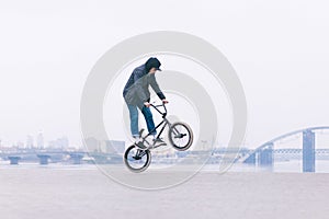 BMX freestyle. Young BMX bicycle makes tricks on the background of a city landscape