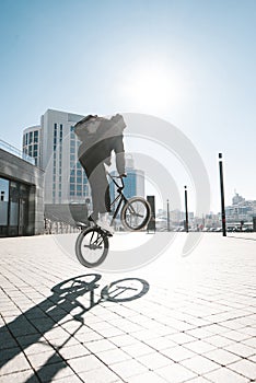Bmx rider jumps on a bike on a sunny day, against the backdrop of urban scenery