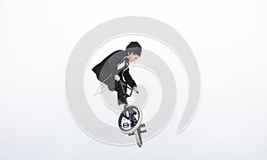 BMX rider makes a TAilwhip trick on a white background. Young man doing tricks in the air on a BMX bike