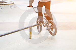 bmx rider in skate park practicing tricks sliding on frame of bike on ramp