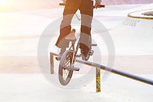 bmx rider in skate park practicing tricks sliding on frame of bike on ramp