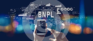 BNPL - Buy Now Pay Later theme with person using a smartphone at night