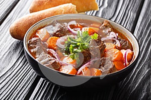 Bo Kho beef ragout in spicy sauce with carrots served with Vietnamese bread close-up in a bowl. horizontal
