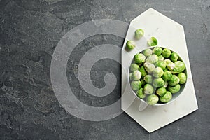 Board with bowl of Brussels sprouts on grey background, top view.