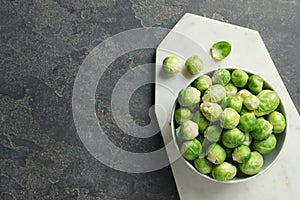 Board with bowl of Brussels sprouts on grey, top view. Space for text