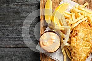 Board with British traditional fish and potato chips on wooden background, top view