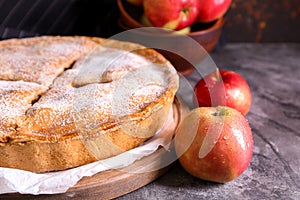 Board with delicious apple pie on dark table, closeup