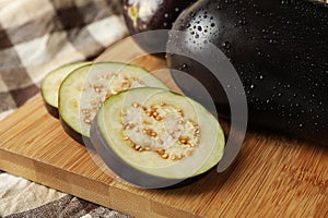 Board with fresh raw eggplants, close up