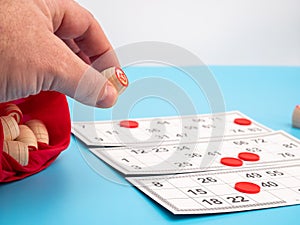 Board game bingo. Wooden barrels with numbers in hand.