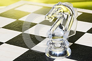 Board game chess. The figure of a transparent glass knight on the chessboard.