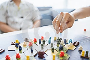 Board game playing concept. People hands hold meeple figures for playing board game on board game field with many figure, dice,