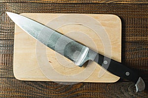 Board with a knife on a wooden background