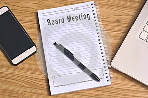 Board Meeting label on notepad with laptop and smartphone