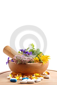 Board with mortar, fresh herbs and pills on white background