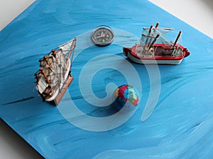A board painted with an ocean pattern with models of sailing ships, a globe and a compass on it