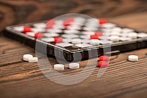 A board for playing checkers with chips on a wooden table, close-up, selective focus