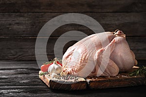 Board with raw turkey and ingredients on wooden table.