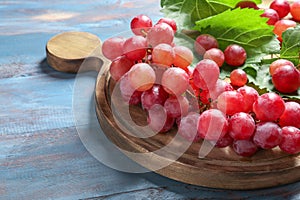 Board with red grapes on wooden table