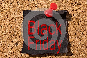 Board and red thumbtack in black paper with reminder about Black Friday
