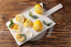 Board with ripe lemons, zest and fresh juice on wooden table