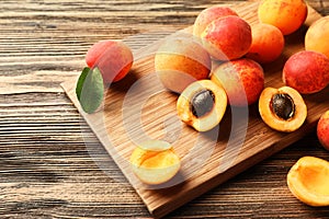 Board with ripe sweet apricots on wooden table