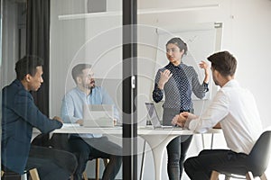 Multi-ethic business people listens indian woman coach giving presentation