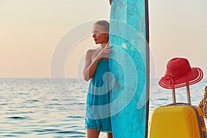 Board for sea surf. Idea of summer time, desire of adventure, copy space. Girl on summer trip, suitcase and hat on sand.