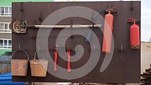 Board with a shovel, fire extinguishers, buckets and axes on construction site.