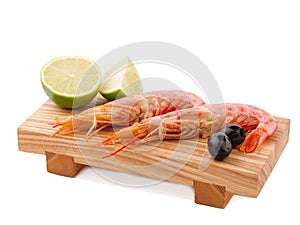 On the board are two royal prawns, lime and several olives. Isolated on white. Close-up.