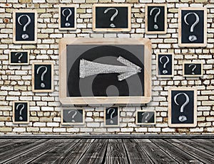 Board on a wooden wall with a chalk drawing of a question mark