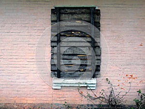 Boarded up old window on the pink wall of the building